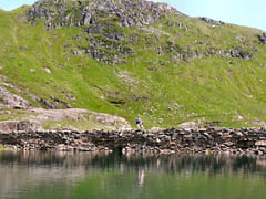 Walkers on the Miners Track causeway crossing Llyn Llydaw. 